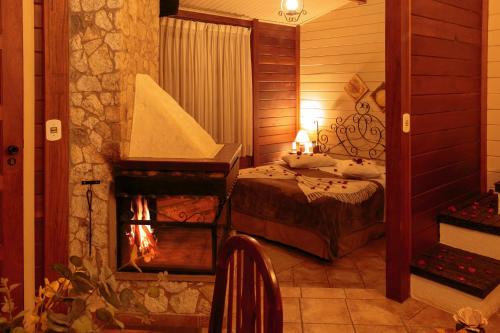a bedroom with a bed and a fireplace at Pousada Varanda das Colinas in Monte Verde