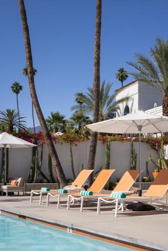 a group of lounge chairs and umbrellas next to a swimming pool at Del Marcos Hotel in Palm Springs