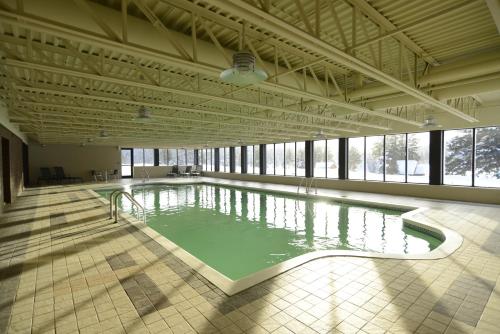 a large swimming pool in a large room with windows at Le Grand R in Saint-Donat-de-Montcalm