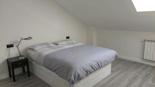 um quarto branco com uma cama e um candeeiro em Apartamento en Posada de Llanes em Posada de Llanes