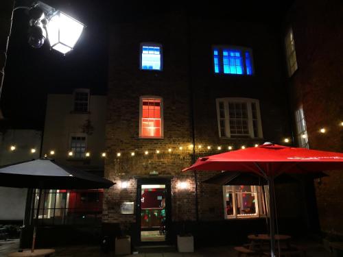 un bâtiment avec deux parapluies devant lui la nuit dans l'établissement The Commercial Bar & Hotel, à Chester