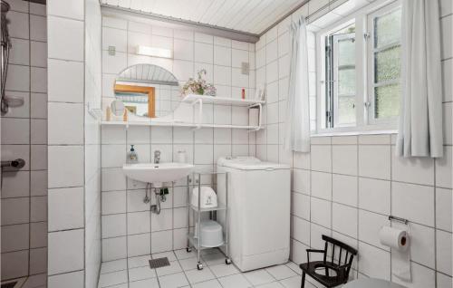 Baño de azulejos blancos con lavabo y aseo en Mlletoften, en Thyholm