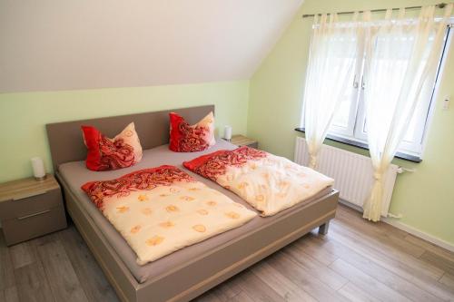 a bedroom with a bed with red pillows on it at Ferienwohnung Schadler in Windeck
