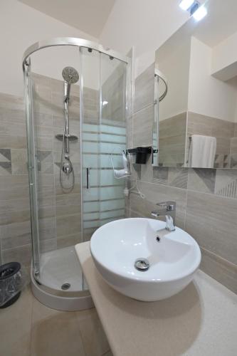 La salle de bains est pourvue d'un lavabo blanc et d'une douche. dans l'établissement Eliseo's rooms, à Triei