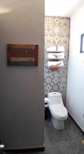 a bathroom with a toilet and towels on a wall at Tres Velas Surf in Celestino Gasca