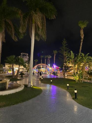 a park at night with palm trees and lights at Executive Royal Tower Apartments - Sky Lounge in El Alamein