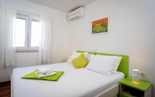 a bedroom with a white bed with a green headboard at Guest House Milan in Hvar