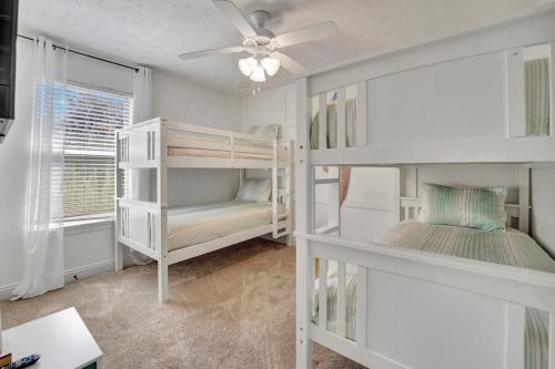a bedroom with white bunk beds and a ceiling fan at Anchors Away in Panama City