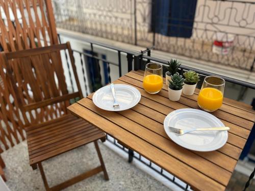 a wooden table with two plates and two glasses of orange juice at Orfeas Luxury Rooms & Studio in Skopelos Town