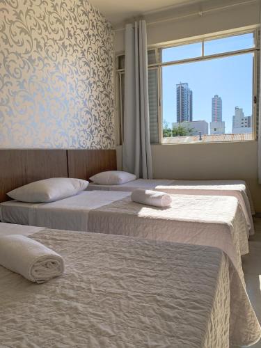2 camas en una habitación con ventana en Hotel Ideal, en Chapecó