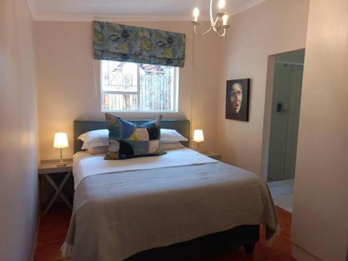 Un dormitorio con una cama grande y una ventana en Cozy Garden Cottage! en Grahamstown