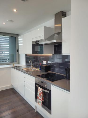 a kitchen with white cabinets and a sink at 2BR Chic London Sleep 9 BP7 in London