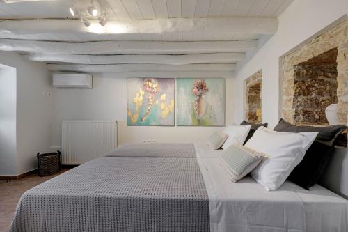 a bedroom with a large bed with two paintings on the wall at Villa Aurora Paxos in Anemogiannátika