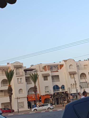 a building with palm trees in front of a street at إقامة النسرين in Yasmine