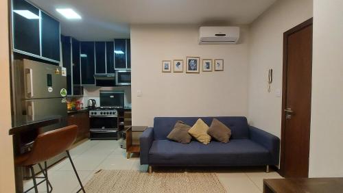 a living room with a blue couch and a kitchen at Apartamento amplio y moderno en el centro de Santa Cruz, con PARQUEO e Internet, cerca de EQUIPETROL in Santa Cruz de la Sierra