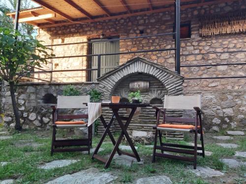 科尼察的住宿－Potamolithos Suites，壁炉前的一张桌子和两把椅子