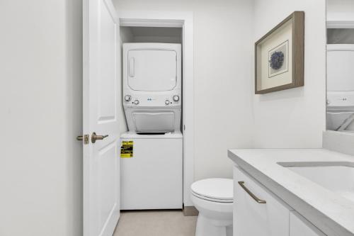 a white bathroom with a washing machine on top of a toilet at Large Family Luxury Beachfront Condo, Private Terrace & Pool in South Padre Island