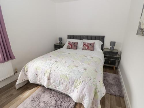 a bedroom with a white bed with pink pillows at The Cottage in Talbenny