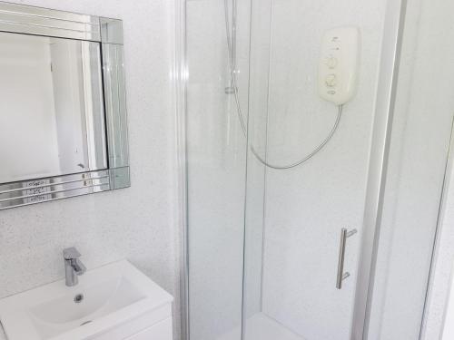 a white bathroom with a shower and a sink at The Cottage in Talbenny