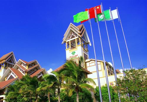 two flags flying in front of a building with palm trees at Dongguan Richwood Garden Hotel in Dongguan