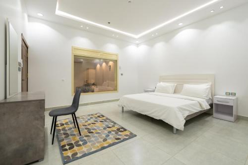 um quarto branco com uma cama e uma cadeira em Taif promise Chalets em Taif