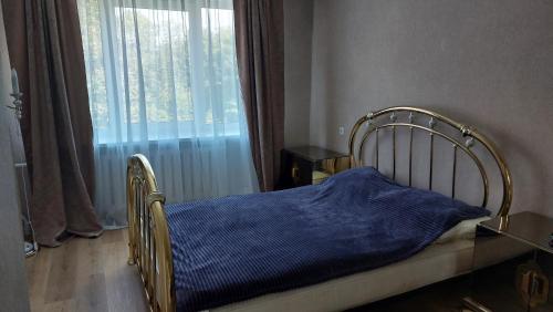 een bed met een blauwe deken in een kamer met een raam bij Лучшее жилье для отпуска в г. Sillamäe in Sillamäe