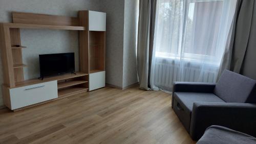 ein Wohnzimmer mit einem TV, einem Sofa und einem Fenster in der Unterkunft Лучшее жилье для отпуска в г. Sillamäe in Sillamäe