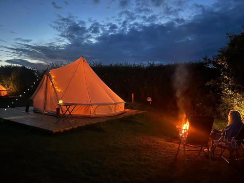 a woman sitting in chairs next to a tent at Roe Deer Meadow at Carr House Farm in Scarborough