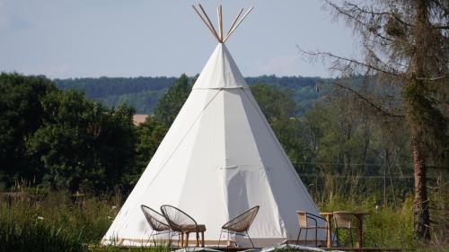 a white teepee with chairs in a field at Les Cabanes Flottantes in Givrauval