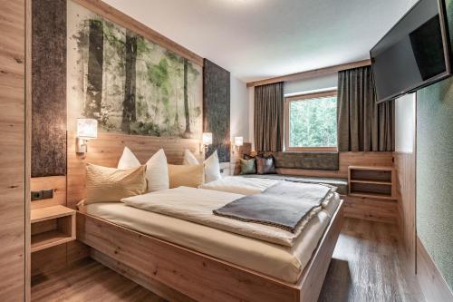 una camera con un grande letto e una TV a schermo piatto di Landhaus Ifangl a Mayrhofen