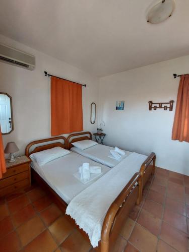 エディプソスにあるKoyias Villageのベッドルーム1室(オレンジ色のカーテン付きのベッド2台付)