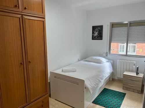 a small bedroom with a white bed and a window at C8 Cómodo piso de 3 habitaciones cerca del centro de Madrid in Madrid
