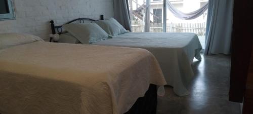 two beds in a hotel room with a window at Miralejos in Punta Del Diablo