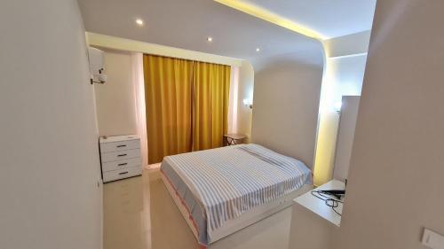 a small bedroom with a bed and a yellow curtain at Kleopatra Carina Apart in Alanya