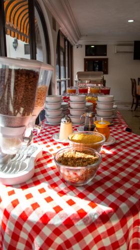 a red and white checkered table with plates and bowls of food at Hotel Casino Plaza in Guadalajara