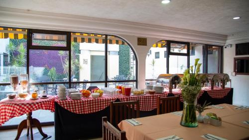 a restaurant with tables with red and white tablecloths at Hotel Casino Plaza in Guadalajara