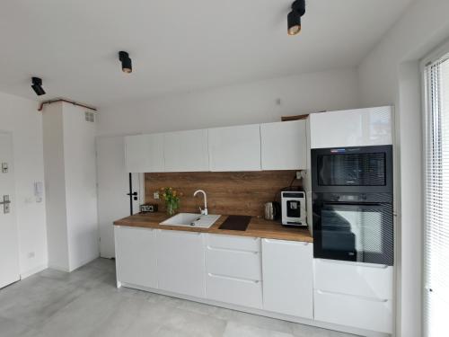 a white kitchen with a sink and a microwave at Bursztynowy dom Międzywodzie Apartament z 1 sypialnią in Międzywodzie