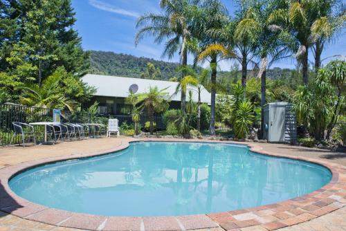 a large swimming pool with a patio and palm trees at Kangaroo Valley Golf and Country Retreat in Kangaroo Valley