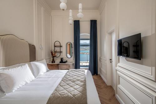 a bedroom with a bed with a television and a window at Palazzo di Sitia Luxury Suites in Sitia