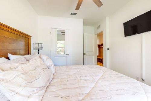 a large white bed in a bedroom with a flat screen tv at The Hammocks in Stuart