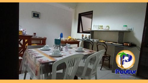 a dining room with a table with chairs and a kitchen at Poutur Pousada in Maceió