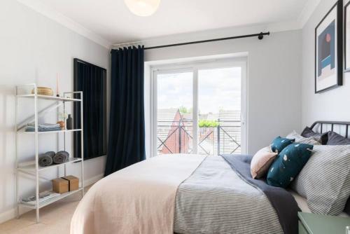 1 dormitorio con cama y ventana grande en Stylish 2 Bed Flat near Station, Parking, Sleeps 6 en Spon End