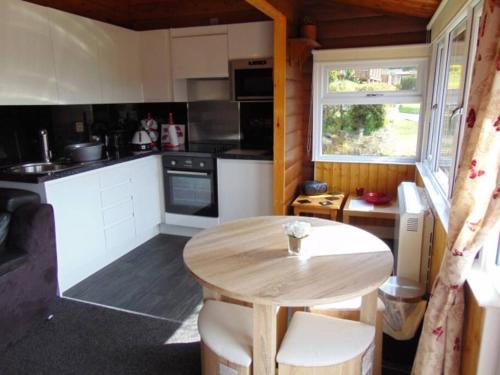 a kitchen with a wooden table and a table and a window at Cabin in Trawsfynydd