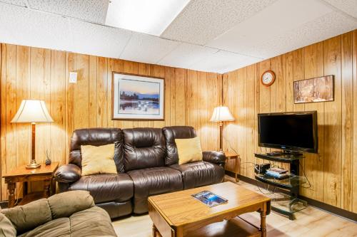 a living room with a leather couch and a tv at Northwoods Paradise in Eagle River