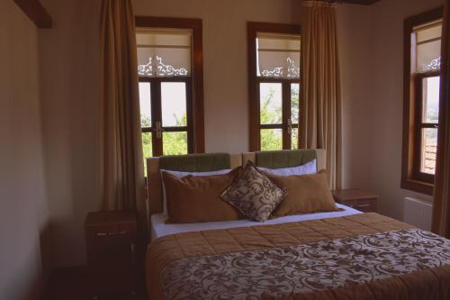 a bedroom with a bed with two windows at Kanoglu Konagi Butik Otel in Akcaabat