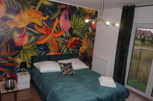 1 dormitorio con un mural de flores en la pared en Villa Laguna Blue, en Swarzewo