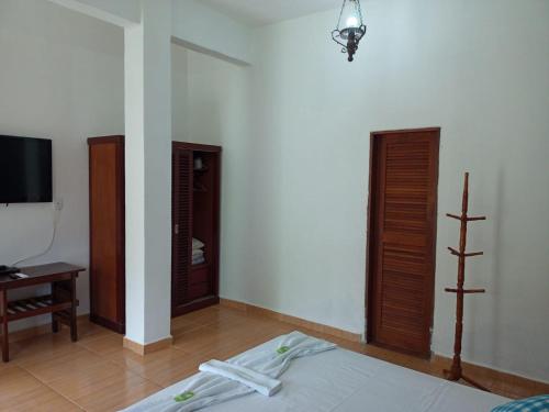 a room with a bed and a tv and two doors at Pousada Nova Conquista in Penedo