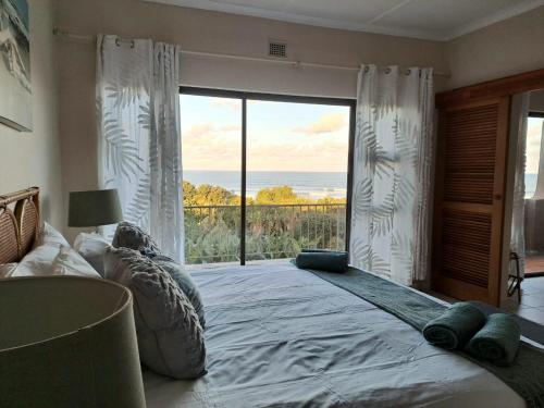 ein Schlafzimmer mit einem großen Bett und einem großen Fenster in der Unterkunft 8 Eden Palms, Palm Beach in Port Edward