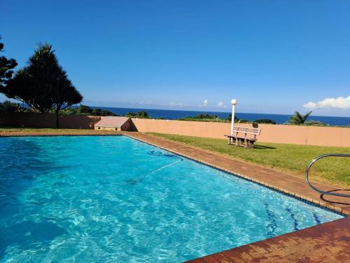 a swimming pool with a bench next to the beach at 8 Eden Palms, Palm Beach in Port Edward