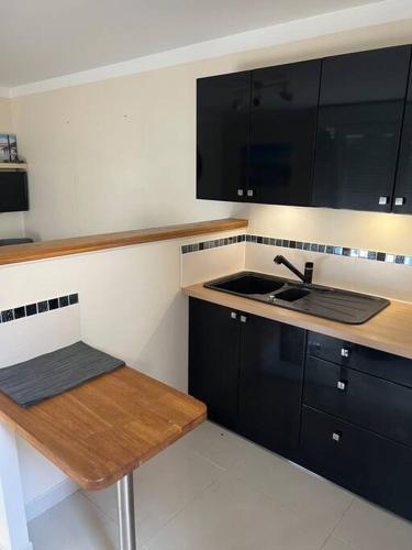 - une cuisine avec des placards noirs et un évier dans l'établissement Le petit paradis, à Gujan-Mestras